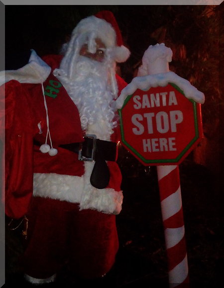 Santa beside a 'Santa stop here' sign