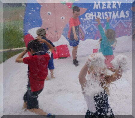 Children playing in fake snow in a summer Christmas