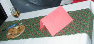 | love santa A table set with a Christmas table cloth, a plate of shortbread as a Santa snack, a glass and a note for Santa