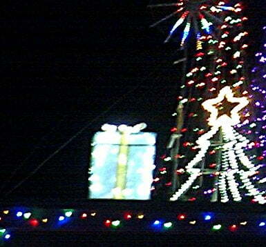 Christmas tree and gift in lights against night sky