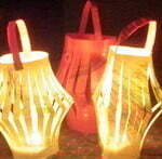 Three child-made paper lanterns lit by candles