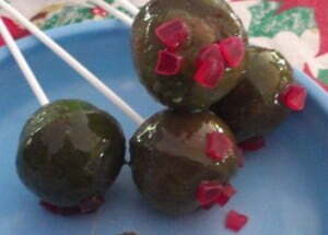 cake pops iced in green with red decorations added