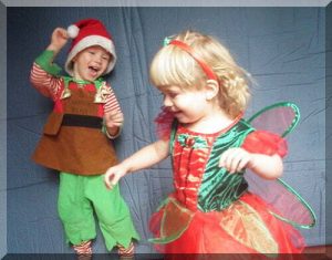 Happy children in Christmas outfits, dressed as Santa's helper and a Christmas fairy