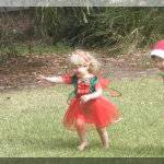 A Christmas fairy and Santa's elf smile and run on grass