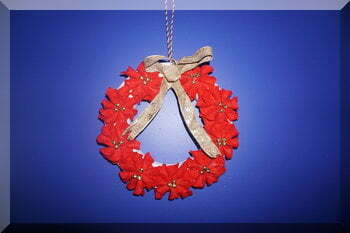 Felt poinsettia wreath handing on a blue wall