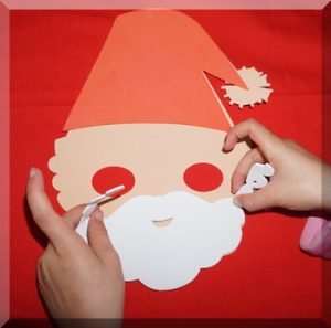 Child sticking a beard otno a foam santa mask