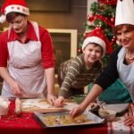 boy and two women cooking Christmas treats in Santa hats