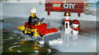 A fire fighter driving a snow plough in Lego City.