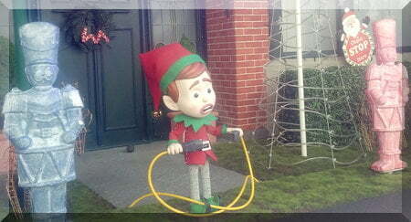 elf holding the ends of a power cord in front of a house