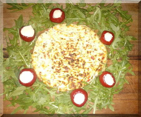 baked cheese surrounded by green leaves to form a Christmas wreath