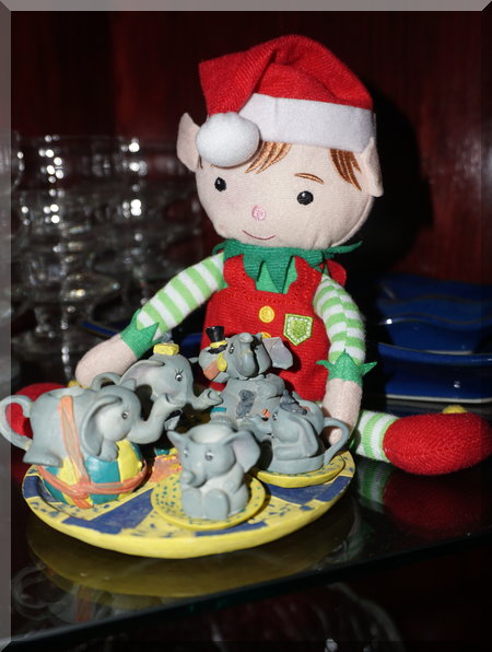 Christmas elf sitting beside some cute ceramic elephants