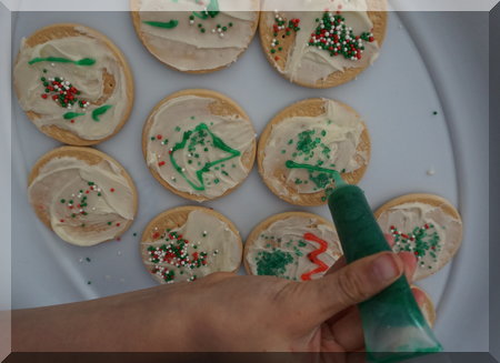 child's hand adding icing to decorate biscuits