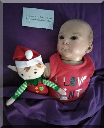 Tinkles the elf in bed with a doll to get warm