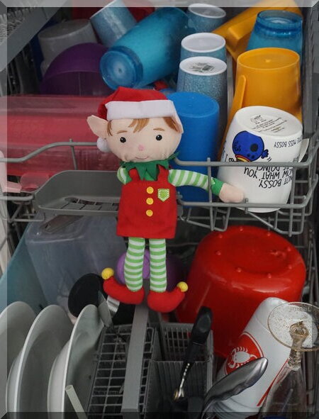 Christmas elf in the dishwasher with clean dishes