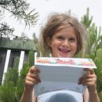 Girl with a huge smile reading a personalised Love Santa letter outside