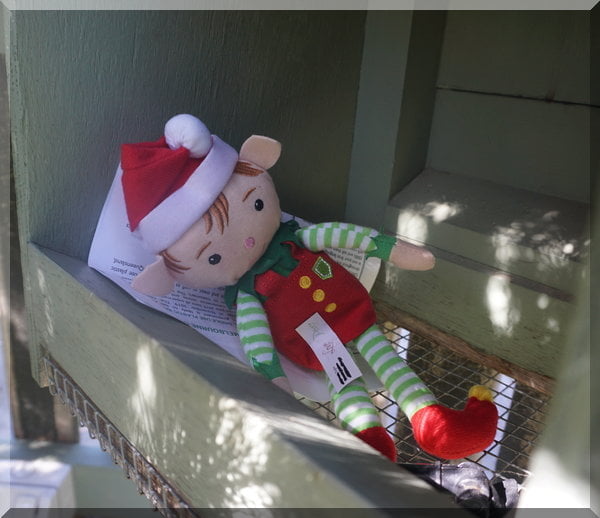 Christmas elf lying inside a letterbox in dappled sunshine