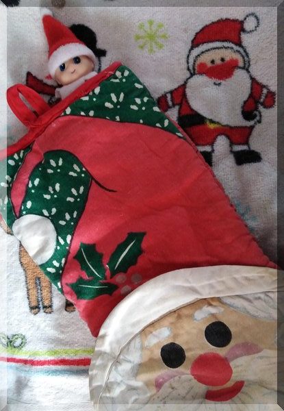 Baby Christmas elf tucked into a Santa oven mitt