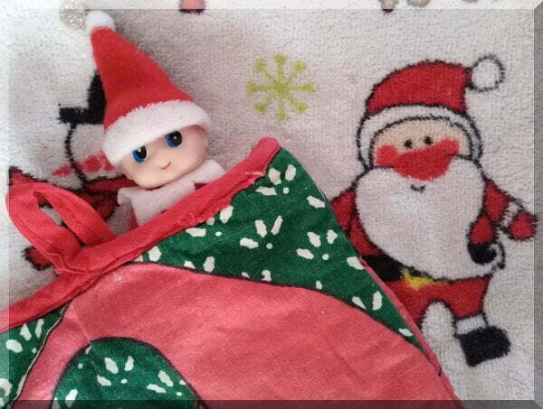 Baby Christmas elf tucked into a Santa over mitt