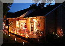 Santa in front of a house with Christmas lights
