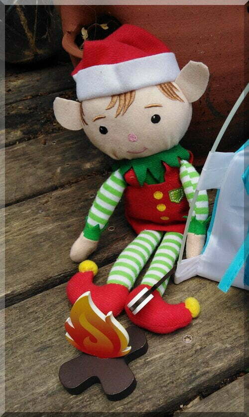 Christmas Elf holding a stick with marshmallow over a campfire