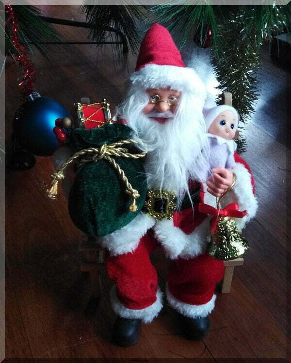 Happy Santa sitting on a chair with a green sack and a baby elf