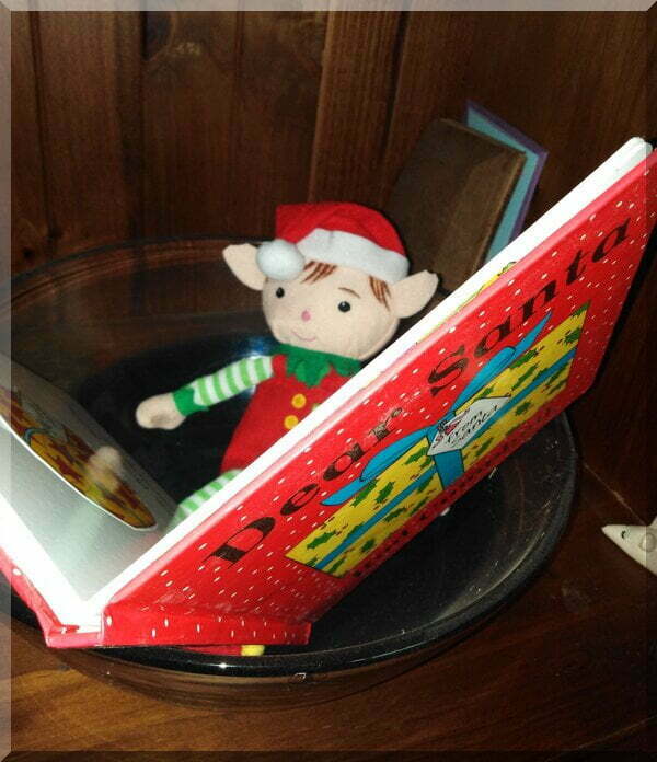 a CHristmas elf reading a picture book, Dear Santa