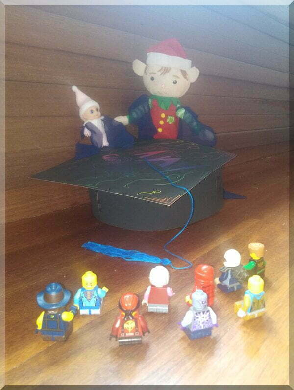 Christmas elves in long gowns, graduating in front of a Lego crowd