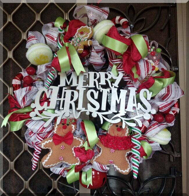Colourful food Christmas wreath with gingerbread people, macaroons, candy canes and a red bell.