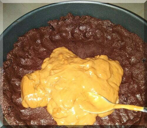 A spoon spreading caramel across a chocolate base in the preparation of a Christmas choc-caramel tart