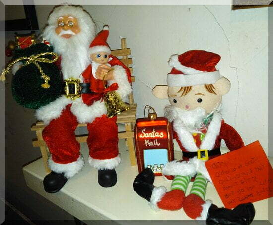 Elves-santa-mantlepiece-550 | love santa Baby CHristmas elf sitting on Santa's lap while the elf is dressed as Santa in wrong sized boots!