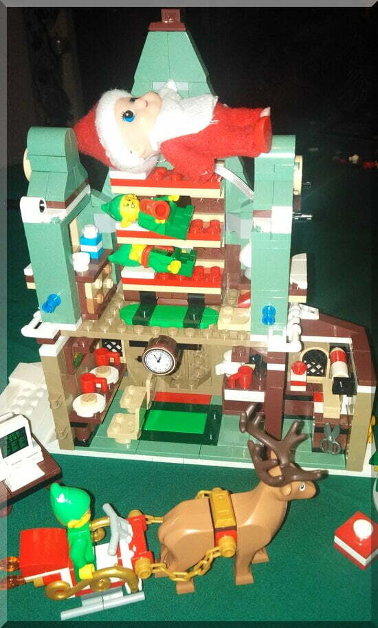 Baby elf lying on the top bunk above other elves in a Lego chalet