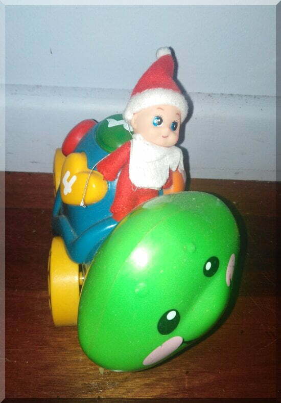 Baby CHristmas elf sitting on a green and blue toy turtle