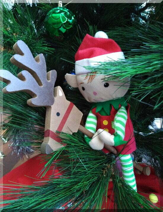 Christmas elf on a hobby-reindeer in the leaves of a Christmas tree
