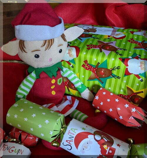Tinkles-pulling-bonbons_500 | love santa A Christmas elf sitting in front of green Christmas presents and holding a bonbon