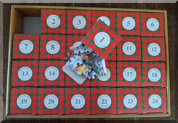 Jigsaw advent box 1 open on other boxes-600 | love santa Twenty-four numbered red boxes in a box. Box one is on top, opened to show jigsaw pieces inside