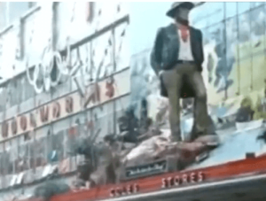 John batman on coles roof burke st 1956 | love santa Large figure of a man in bush clothes of the 1830s standing on a roof above a sign saying Coles Burke St